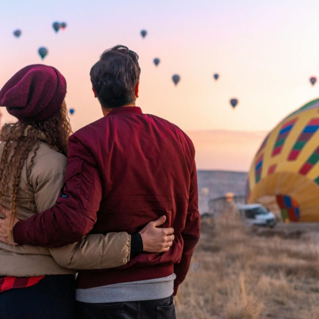 couple standing and watching a hot air ballon get ready for flight